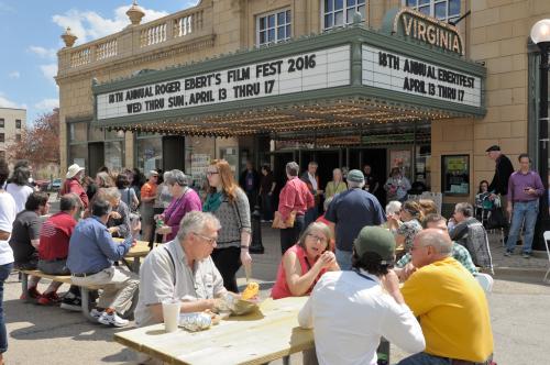 Ebertfest festival goers sitting at picnic tables under the Virginia Theatre marquee